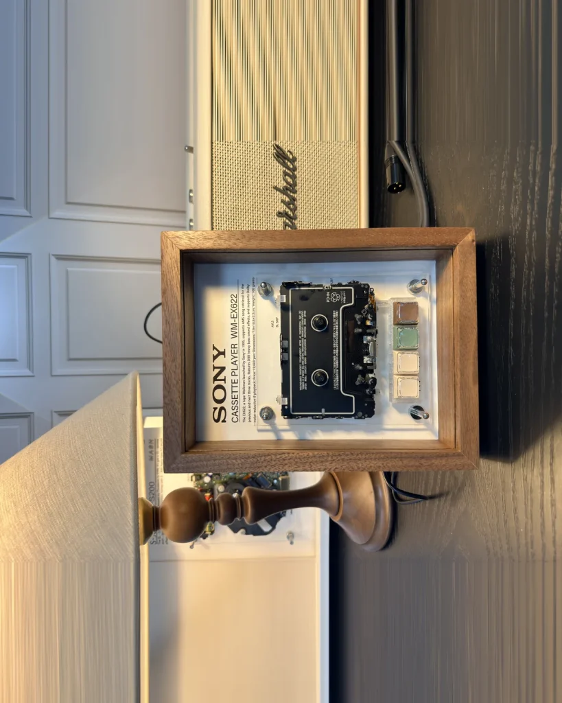 Framed vintage cassette player hanging on a wall at an angle