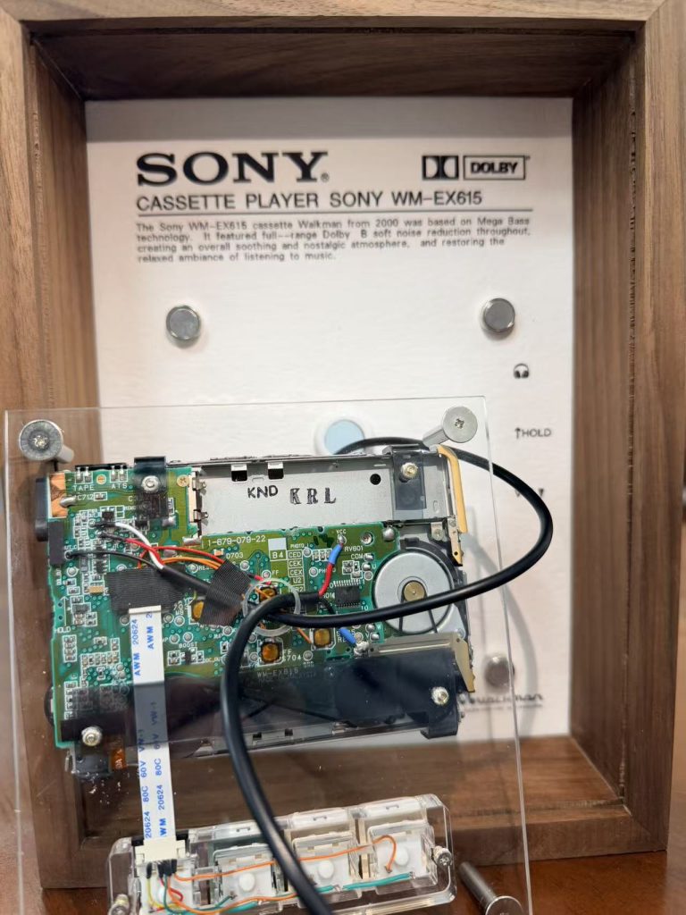 Back of a framed Sony Walkman opened up to show the drive mechanism and circuit board
